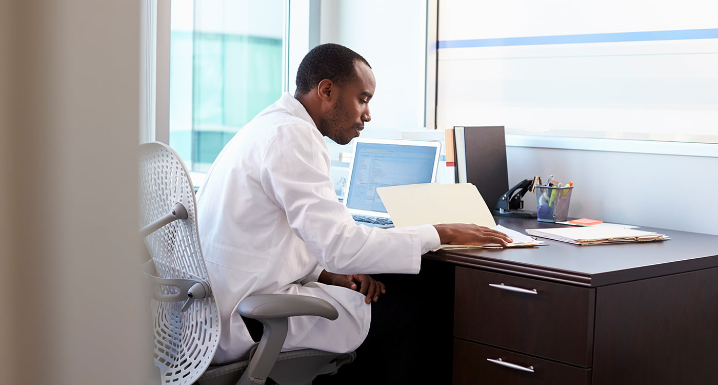 a doctor sitting as his desk looking in a folder